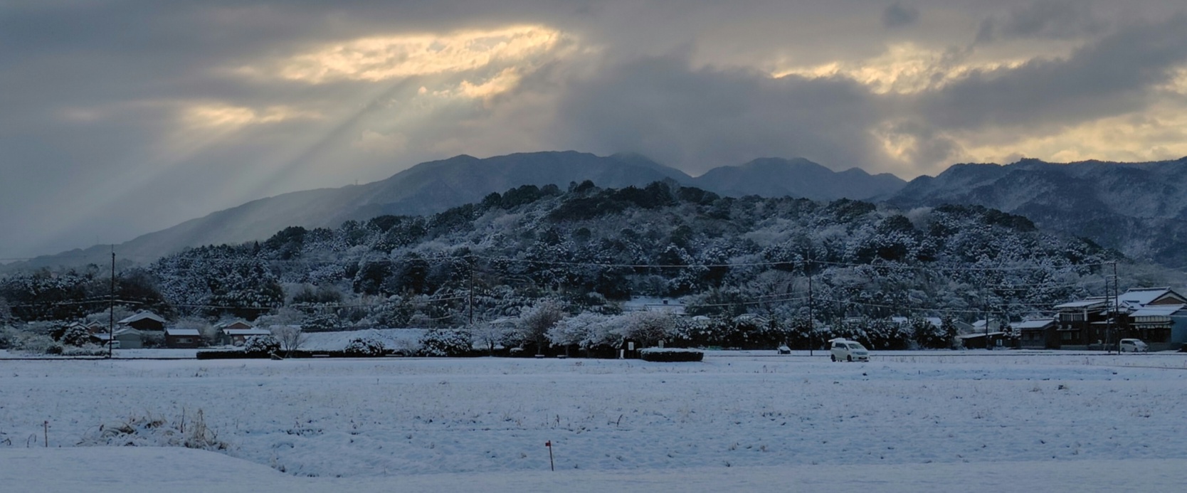 藤原京から見た雪化粧の天香具山。雲の隙間から光が差し込む様子